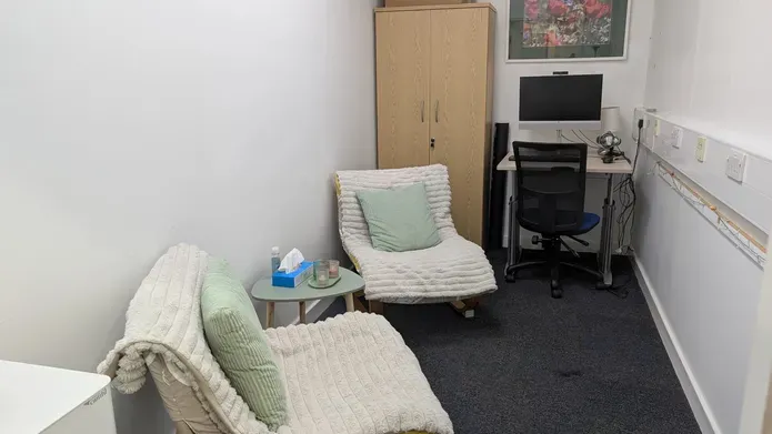 Two chairs with cushions covered with blankets with a computer, desk and office chair situated in a quiet room 