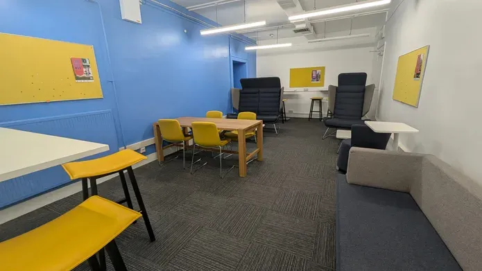 A room with two high back chairs, table surrounded by chairs and a sofa