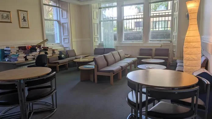 A room with soft furnishings and two round tables with chairs 