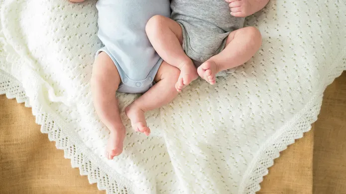 The lower body of two babies, side by side.