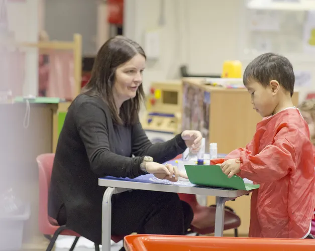 a woman teaching a small boy