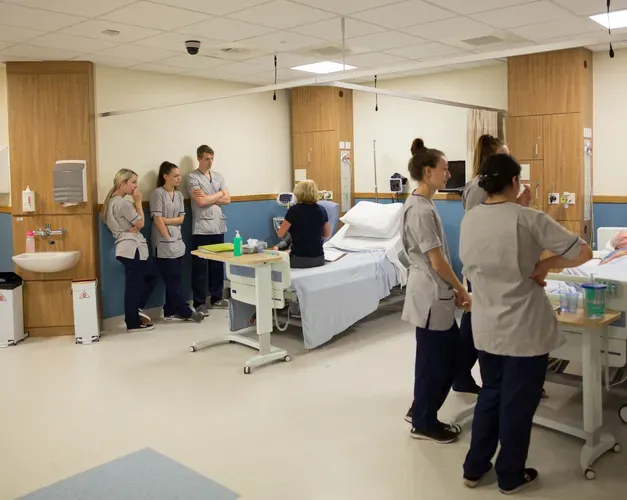 Student nurses attend to actors playing patients in a simulated ward