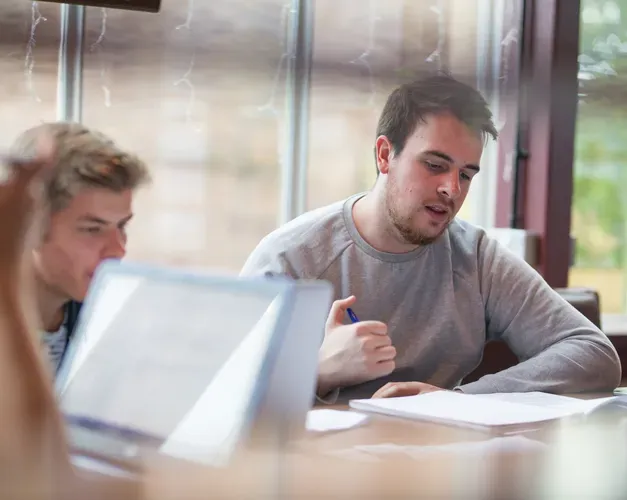 Two students study in The Liar bar using laptops and books