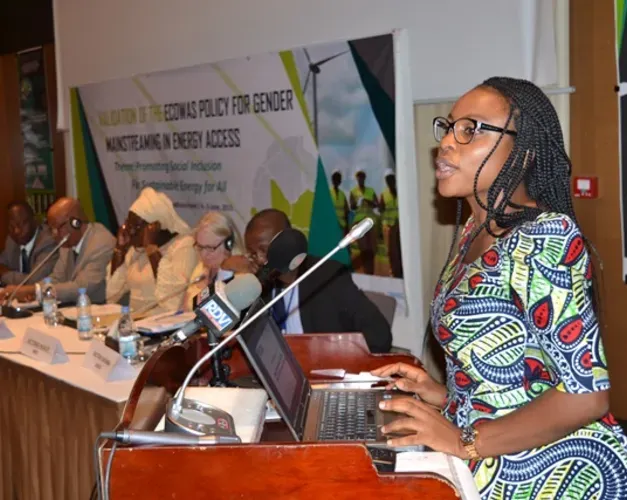 a woman standing at a podium talking 
