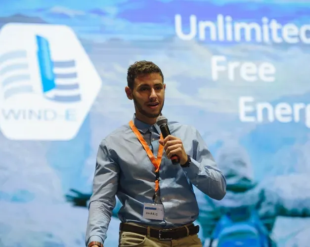 Harris at the competition, bright blue screen with unlimited energy written on it 