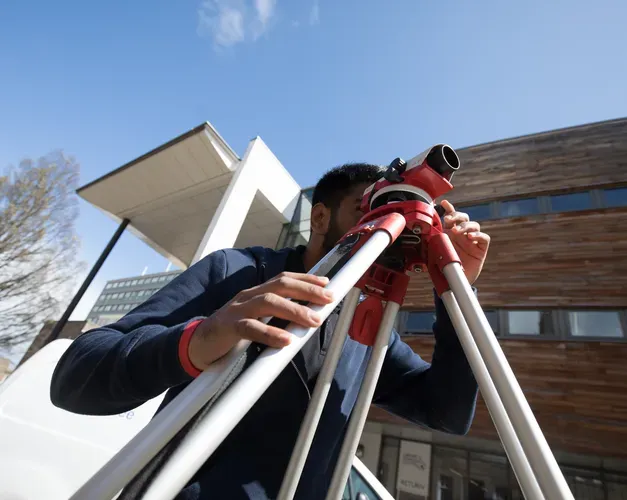 engineering student outside with measurement tool