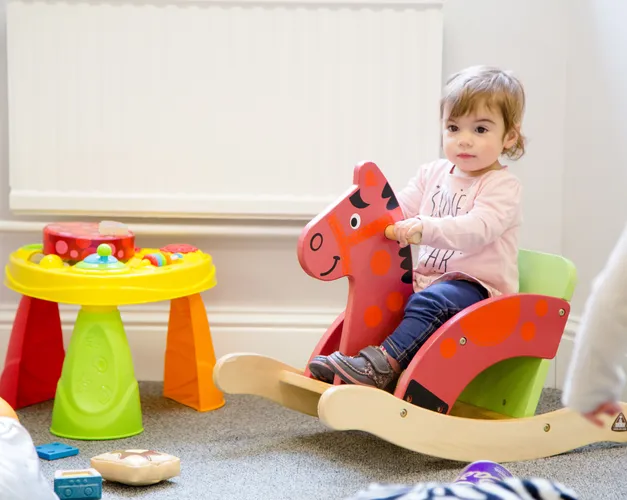 A young girl plays on a rocking horse