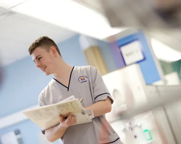 A student nurse in a hospital holding notes