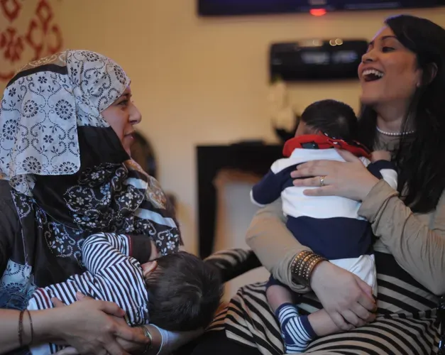 two mothers laughing and holding their babies