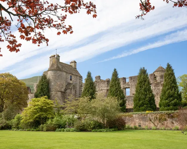 Falkland Castle, a part ruin in Fife, with sky showing through some windows and well kept conical trees at the front