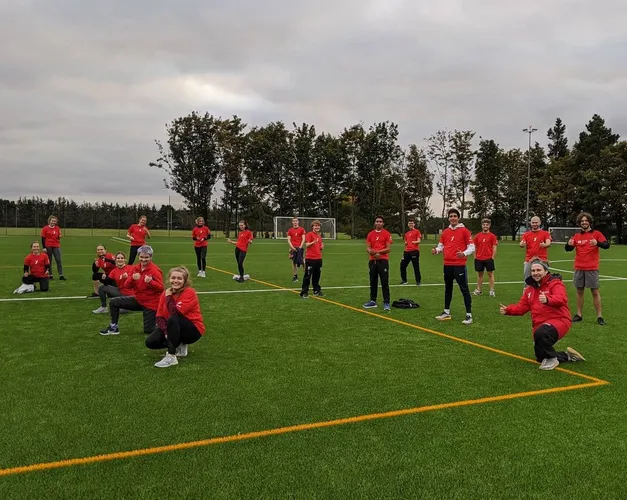 group of students in red sports attire on green grass pitch 