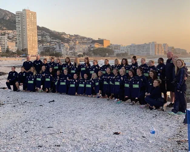 the Scottish womens rugby team posing for a photograph with snow on the ground and some buildings behind them