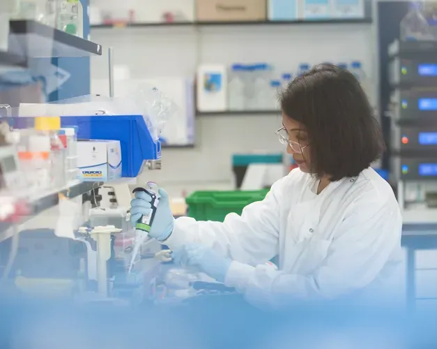 Scientist using syringe to fill up container in lab