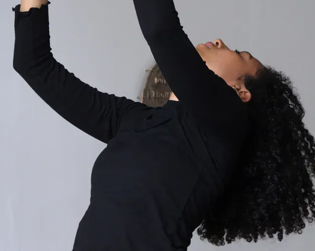 A women with her arms in the air and head back in an exhibition room