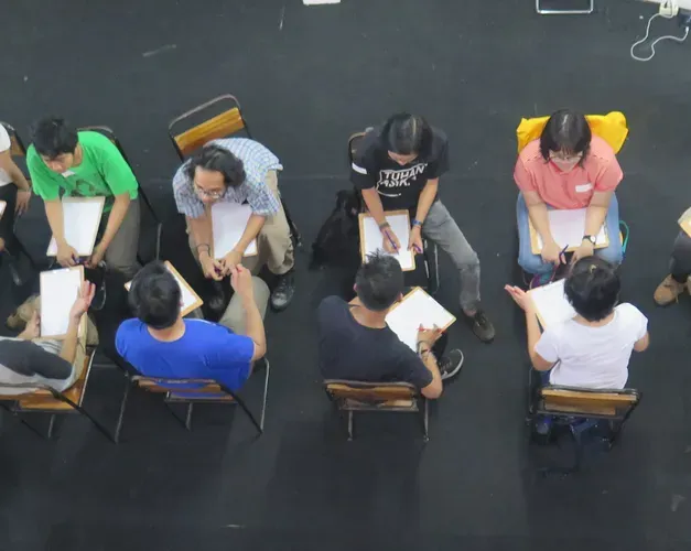 A view from above a row of people sitting in chairs on a black floor