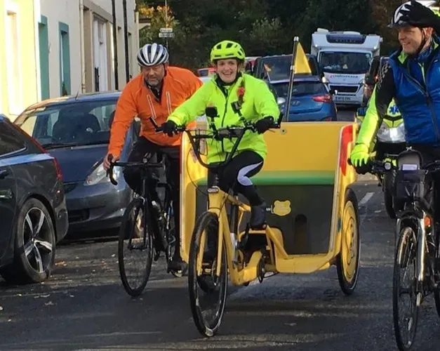 two men riding bikes following a young girl in hi-vis gear riding a rickshaw