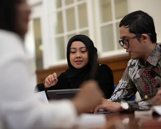 A couple of students sitting around a table looking at a laptop