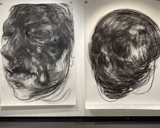 Large scale charcoal portraits of a woman's face and skull