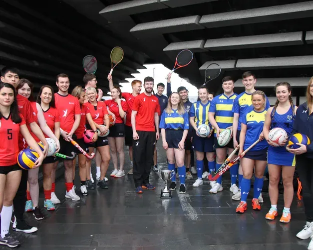 a group of young sports people holding their sport equipment posing under structural arch