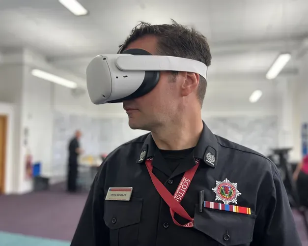 A man from the Scottish Fire and Rescue Service stands with a white VR headset mounted on his head