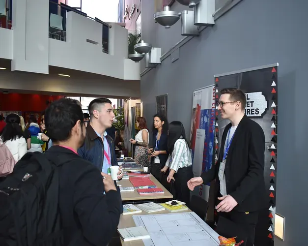 People standing in the Dalhousie Building foyer visiting tables with books and posters for the Venture 2021 competition