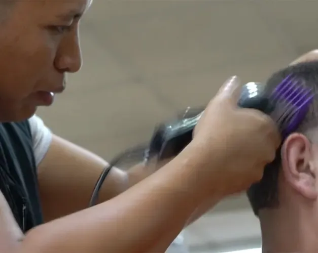 A close up of a  barber shaving a customers hair
