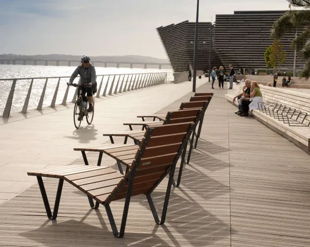 wooden deckchairs on boardwalk with cyclist coming past