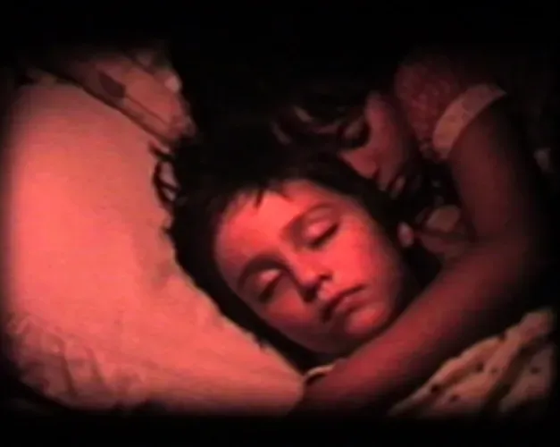 Two sleeping children hugging laying down on a pillow. The shot is in red.
