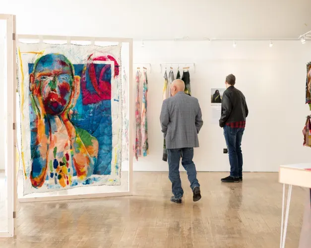 men looking at abstract art on white canvases