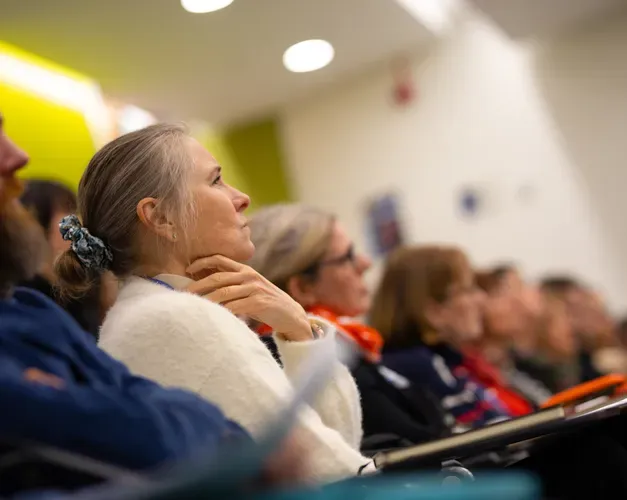 A row of men and women in a lecture theatre listening to a talk.