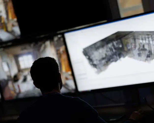 A man looks at multiple computer screens, which are out of focus