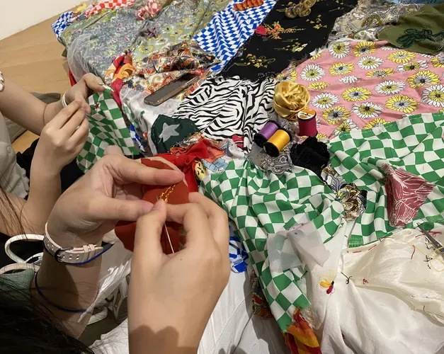 Photo of hands sewing a patchwork of colourful decorative fabrics