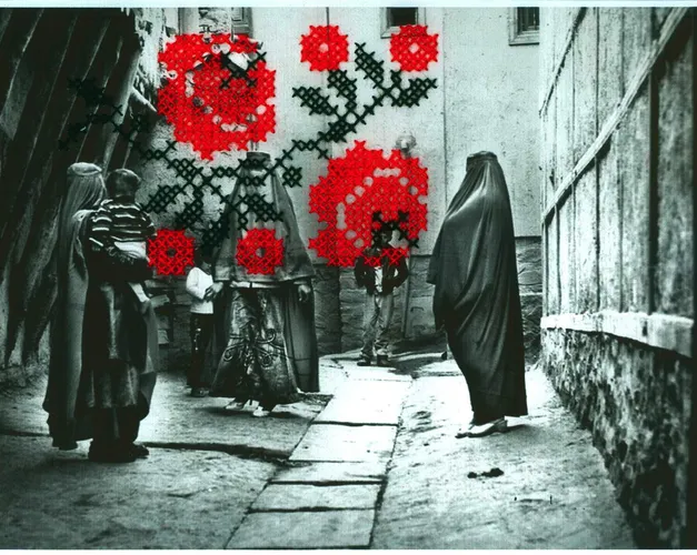 A black and white photograph of people in an alley, obscured by bright red thread