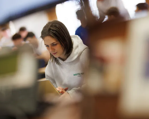 A student in a lecture theatre looking at her laptop