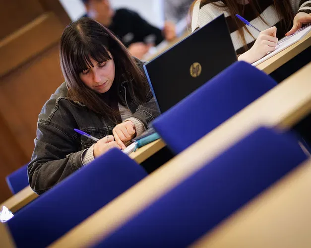A student taking notes while in a lecture