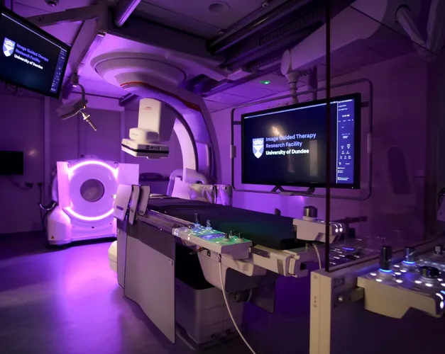  A room featuring a large screen mounted on the wall and medical imaging equipment in the foreground