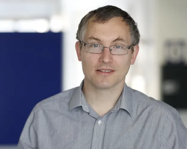 Professor James Chalmers, wearing a grey shirt and glasses in a medical setting