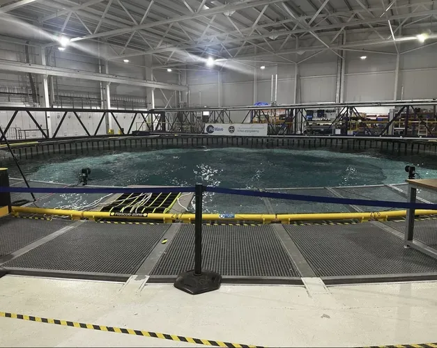 Large circular indoor pool with grills and barriers around it. Water is clearly moving and swelling in centre 