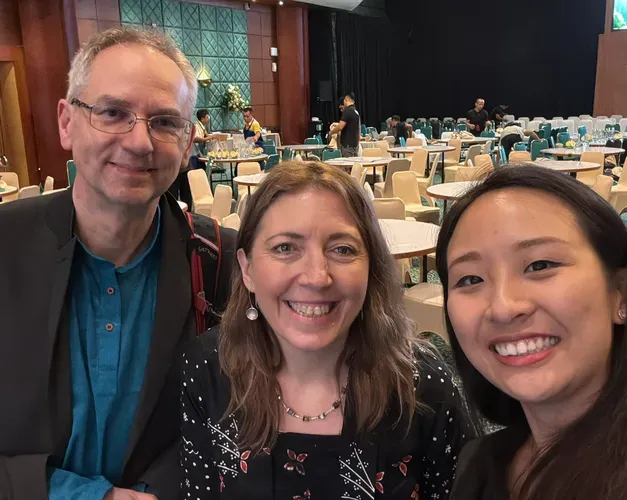 close up shot of three people in front of conference tables and chairs