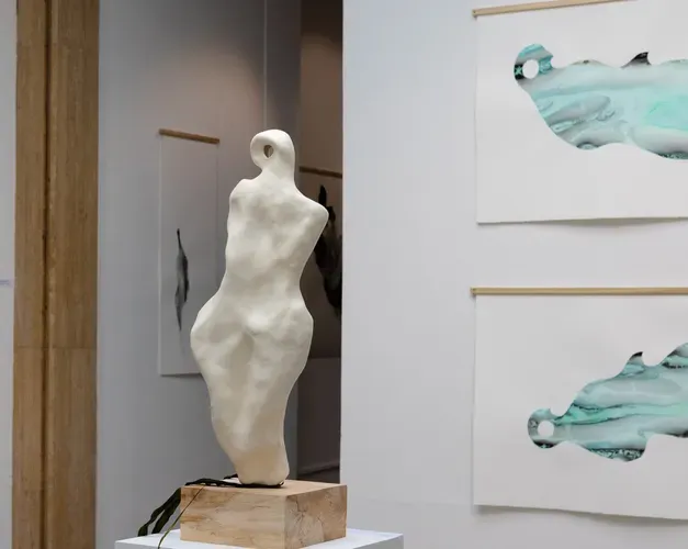 image of art exhibit, with a sculpture of a torso on the left hand side and two abstract art images on the right hand side, which are turquoise coloured shape