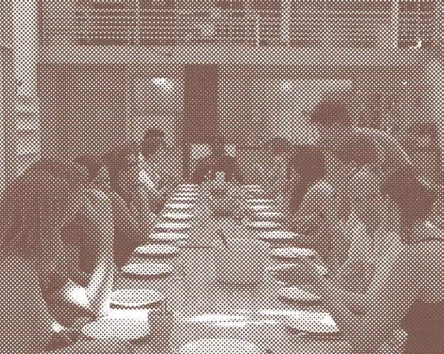 A group of people gathered eating around a long table