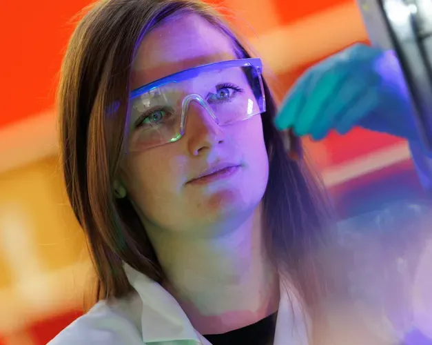 woman looking at computer screen while wearing safety glasses