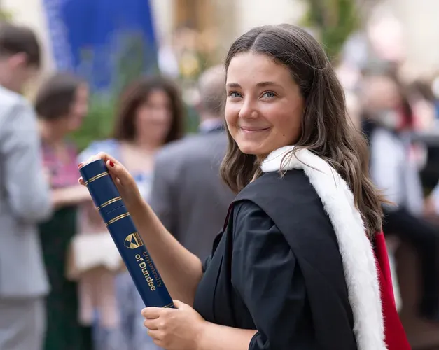 student holding graduation scroll