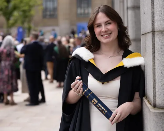 student holding graduation scroll