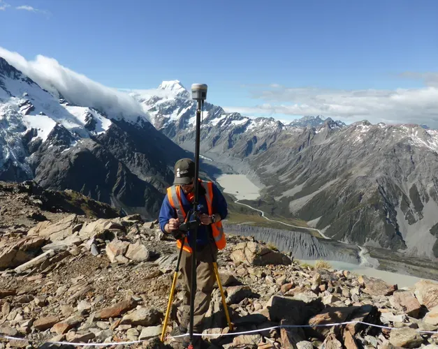 Man setting up research camera at the top of a mountain