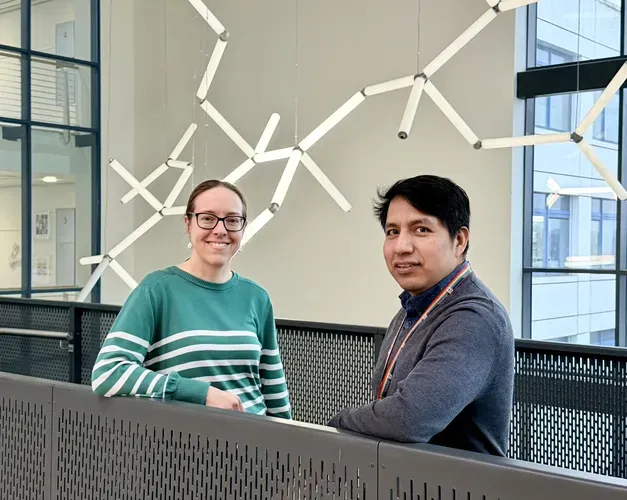 Two people stood smiling in front of a light installation