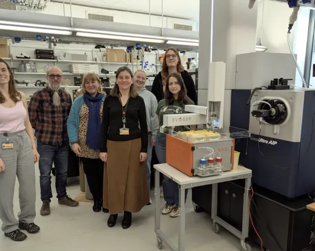 A group of staff stand together in a lab with several types of equipment around them
