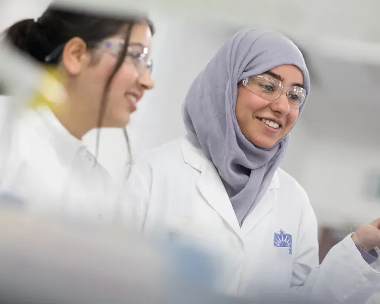 Two students in lab coats in a lab