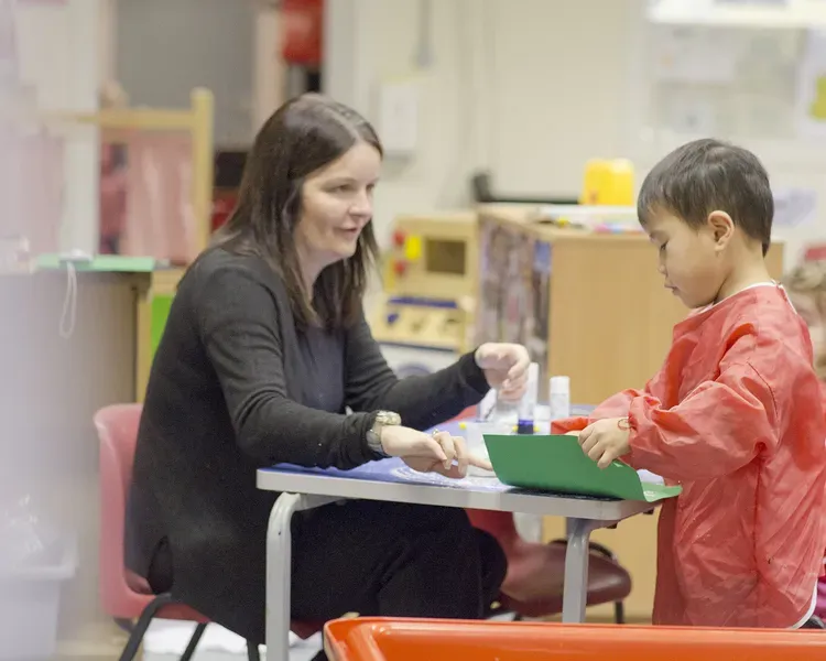 a woman teaching a small boy