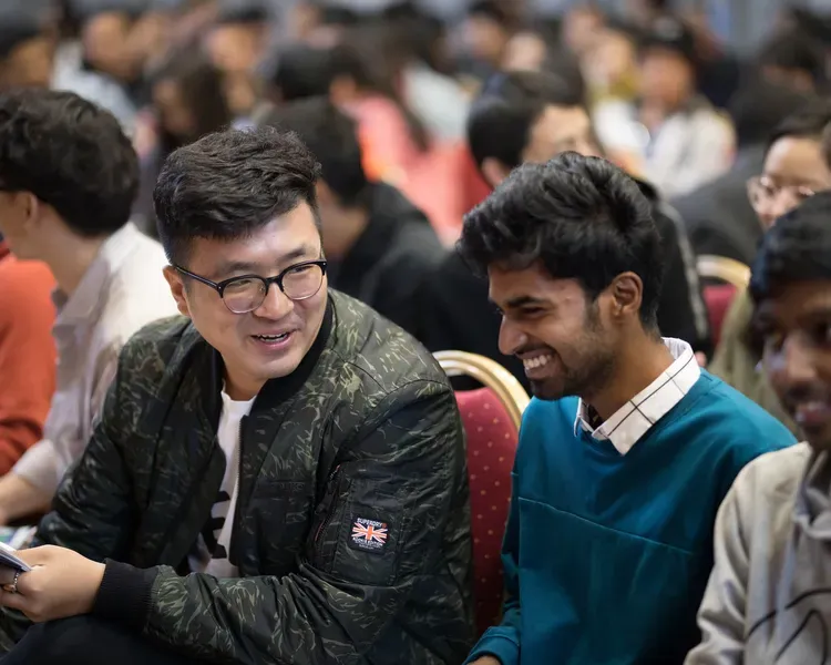 Two students chatting in a lecture theatre